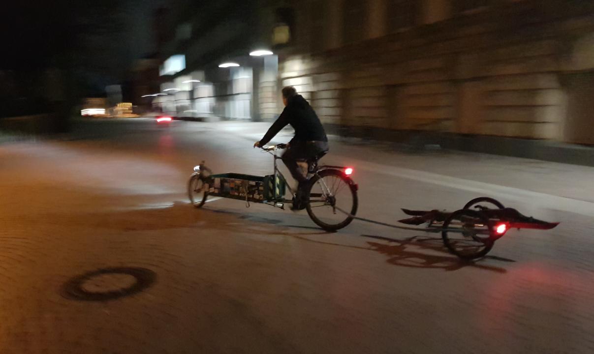 Lastenrad, das den Anhaenger in der Dunkelheit zieht.