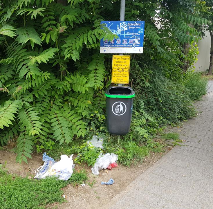 Muell liegt um einen Muelleimer verteilt, der augenscheinlich leer ist.