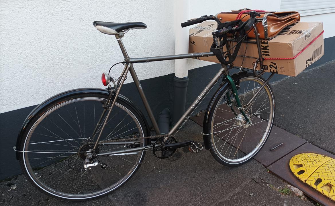 Symphony lehnt an einer Wand, mit grossem Paket auf dem Frontgepaecktraeger.