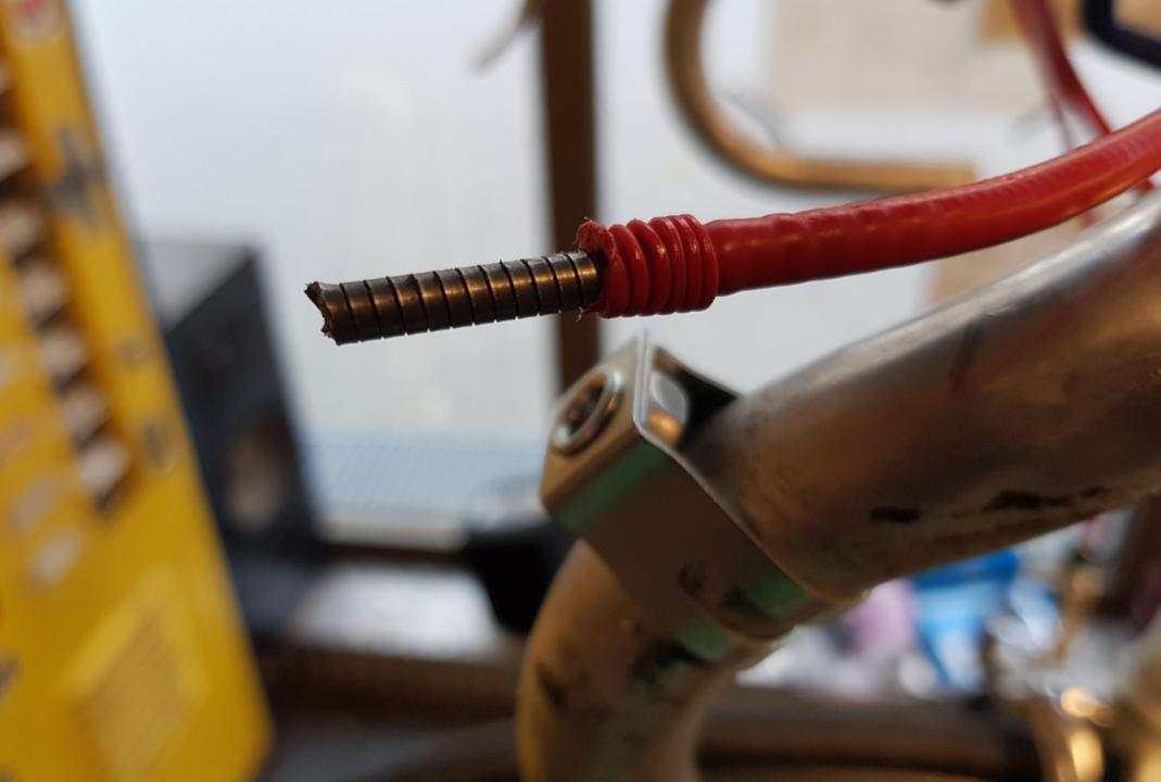 Zurueckgeschobener Kunststoffmantel einer roten Zughuelle.